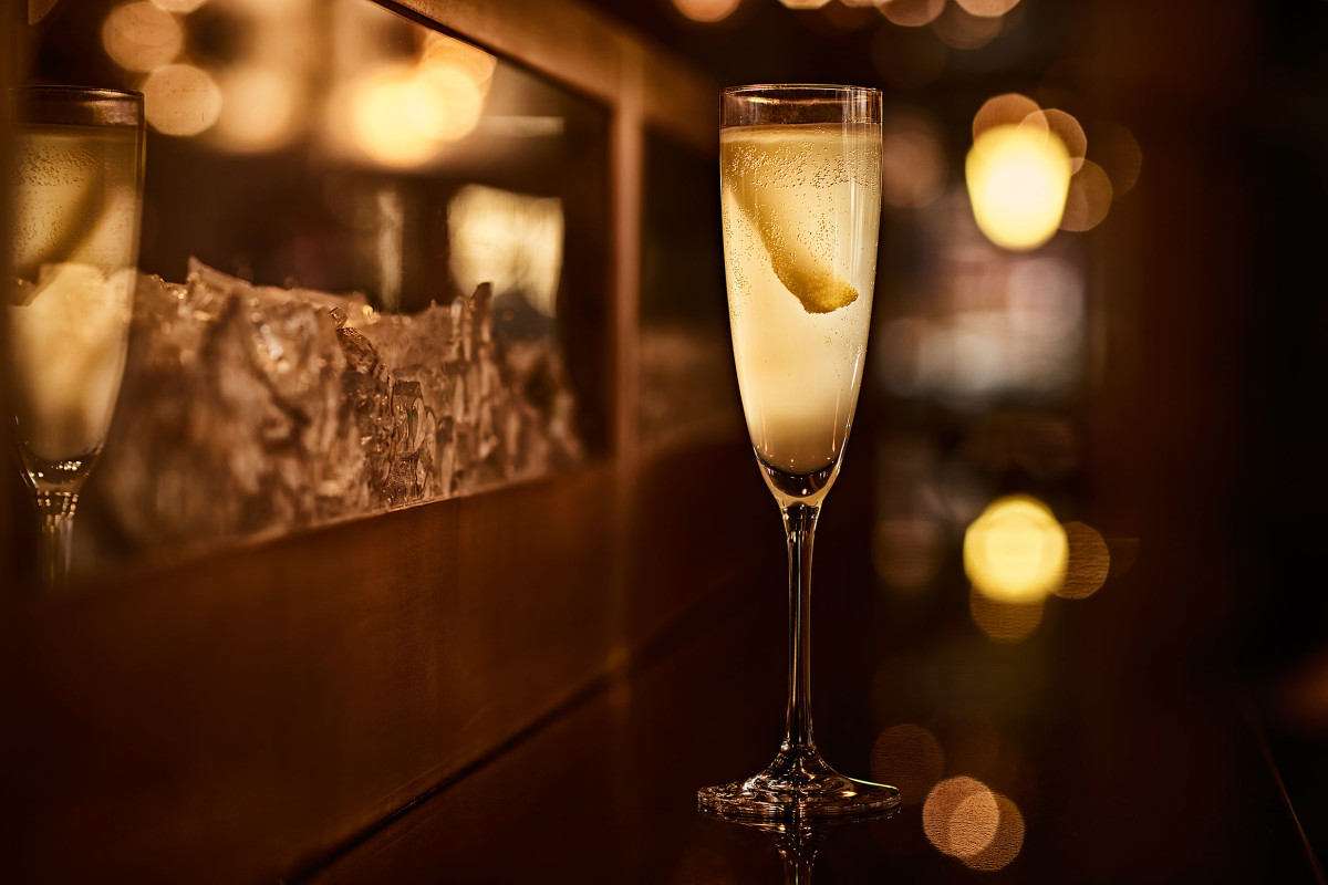 A detail shot of a cocktail in a flute glass with a lemon twist.