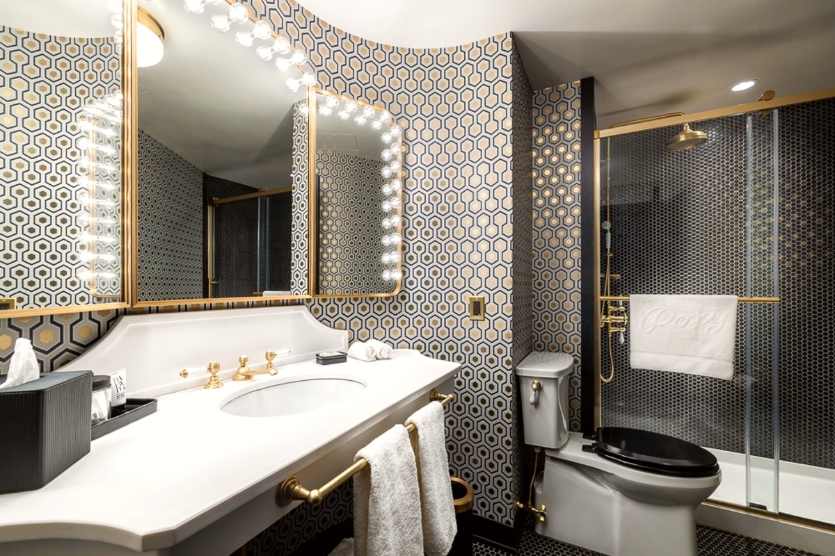 Bathroom vanity mirror, white sink, and black-tiled shower.