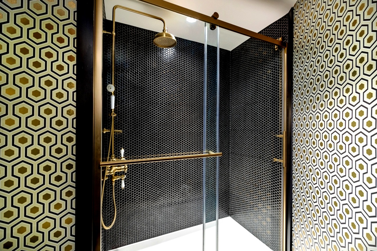 Bathroom vanity mirror, white sink, and black-tiled shower.