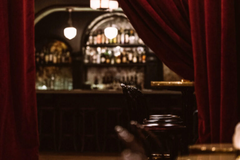 A red curtain is pulled back to reveal the Django Jazz Club bar.