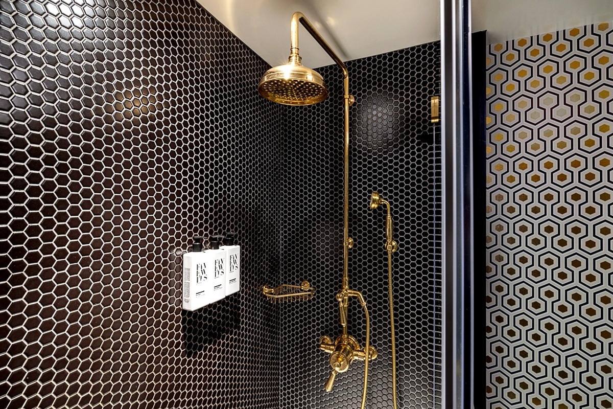 Black tiled shower with gold plumbing hardware.