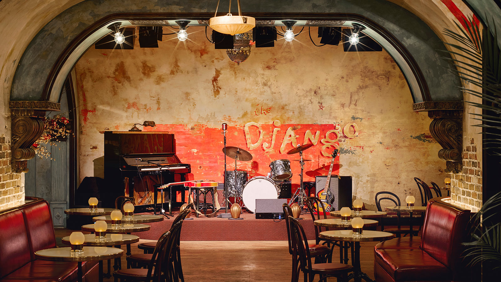The Django stage with all its instruments including a piano, a drum set and a guitar. There are candlelit tables lining the room.