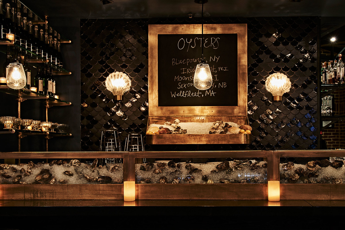 Fully stocked oyster bar with oysters on ice. Black and gold design and decor.